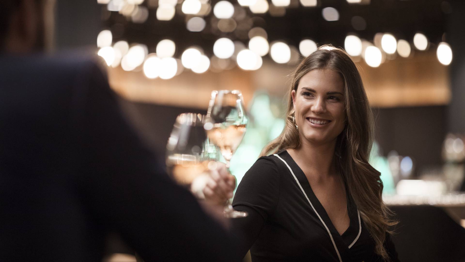 Frau stoßt mit Glas Wein an