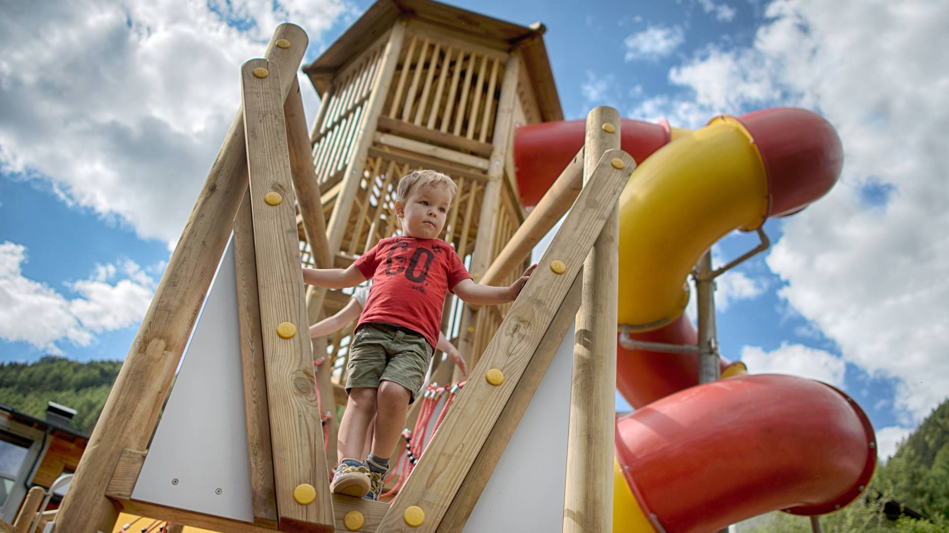 Junge steht auf dem Klettergerüst mit Rutsche