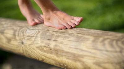 Kinderfüße balancieren über eine Holzstamm