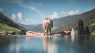 Frau mit blonden Haaren im Pool mit Blick auf die Region Südtirol