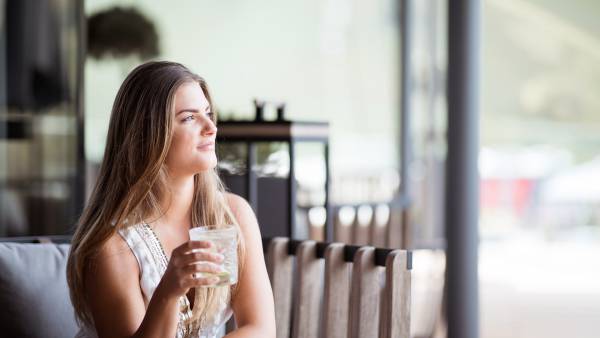 Frau genießt Drink auf der Dachterrasse der Skybar