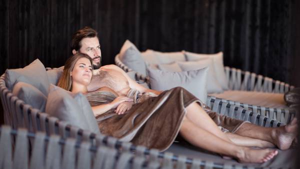 Paar liegt auf Liegen im Ruheraum des A&L Wellnessresorts im Ahrntal